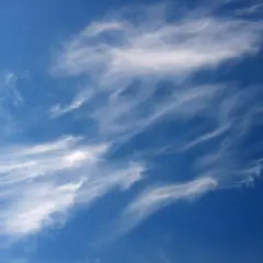 Ciel bleu profond parsemé de nuages fins et filandreux, comme des pinceaux de lumière dans le ciel.