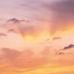 Le ciel est rose, teinté d'orange et de jaune, avec des nuages sombres. Une douce lumière filtre, expliquant pourquoi le ciel est rose.