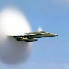 Un avion de chasse franchit le mur du son, créant un nuage de condensation spectaculaire autour de lui.