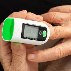 Doigt âgé sur oxymètre mesurant le taux d'oxygène dans le sang. Affichage de 96% SpO2 et 74 bpm.