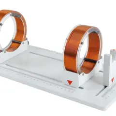 Deux bobines de Helmholtz en cuivre sur un support blanc avec une règle graduée.