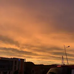 Le ciel est orange, un spectacle magnifique au-dessus d'un hôtel et d'une voiture.