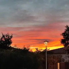 Ciel embrasé par un coucher de soleil couleur orange et rose, avec des nuages gris. Un lampadaire éclaire la scène.