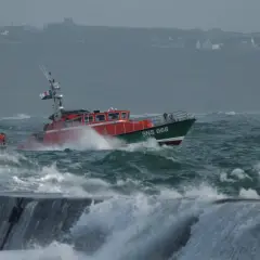 Bateau de sauvetage SNS 068 naviguant dans une mer agitée, sous un fort coup de vent. Les vagues déferlent sur la proue.