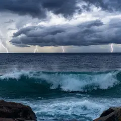 Orage spectaculaire sur l'océan Pacifique, éclairs zébrant un ciel menaçant au-dessus de vagues déferlantes.
