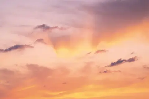 Le ciel est rose, teinté d'orange et de jaune, avec des nuages sombres. Une douce lumière filtre, expliquant pourquoi le ciel est rose.