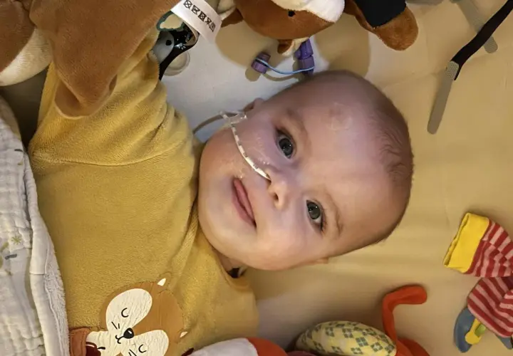 Un bébé avec une sonde nasogastrique, entouré de peluches. L'espoir d'une vie longue malgré la maladie de Pompe.