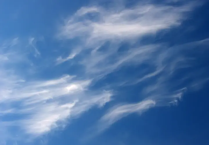 Ciel bleu profond parsemé de nuages fins et filandreux, comme des pinceaux de lumière dans le ciel.