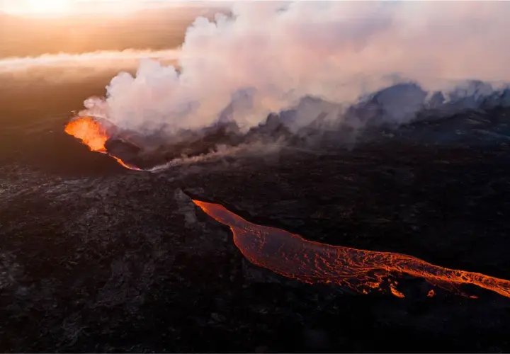 Éruption volcanique en Islande : la lave incandescente coule sur le paysage sombre, baignée par la lumière dorée du soleil couchant.
