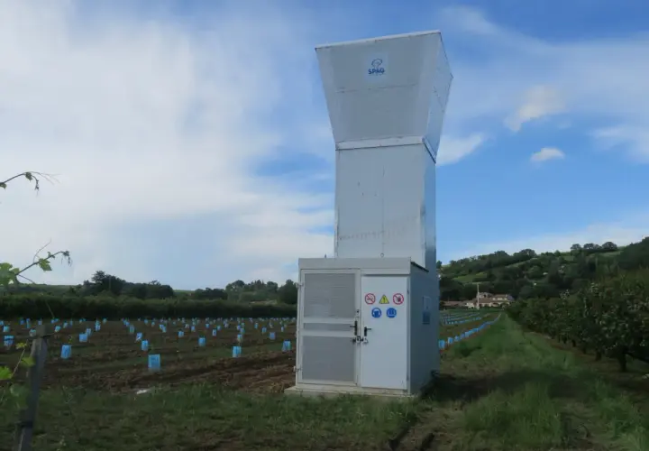 Un canon anti-grêle SPAG se dresse dans un vignoble, prêt à protéger les jeunes plants des orages.