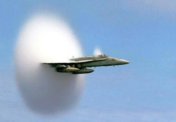 Un avion de chasse franchit le mur du son, créant un nuage de condensation spectaculaire autour de lui.