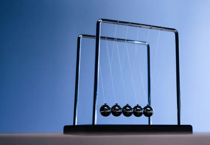 Un pendule de Newton, avec ses billes d'acier suspendues, illustre la conservation de l'énergie et de la quantité de mouvement. À quoi ça sert ? À observer la physique en action !