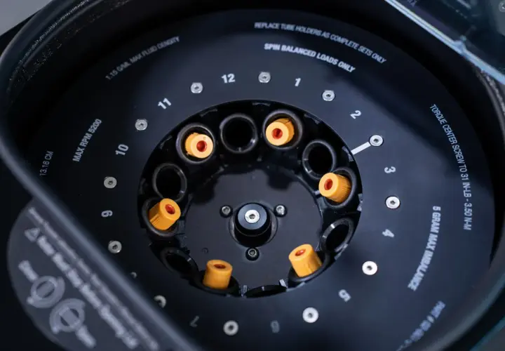 Rotor de centrifugeuse avec des tubes à essai orange. Indique "MAX RPM 5200" pour la centrifugation.