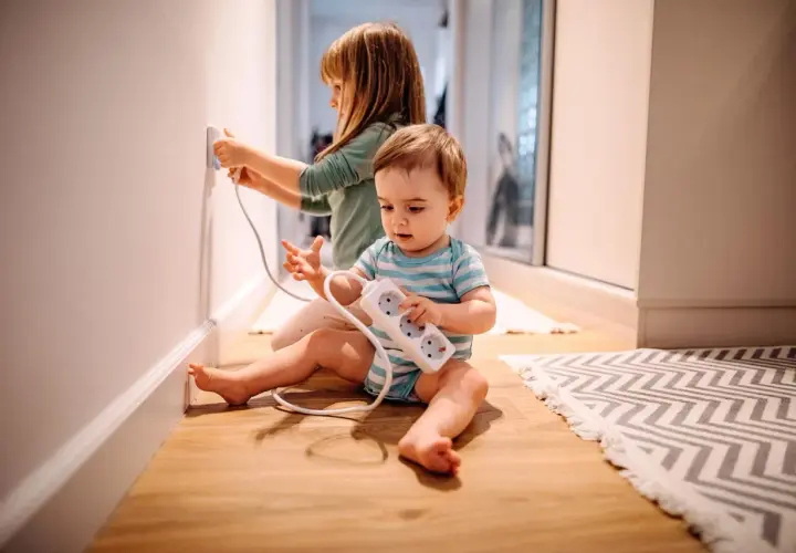 Deux enfants jouent avec des prises électriques, un danger potentiel d'électricité dans le corps.