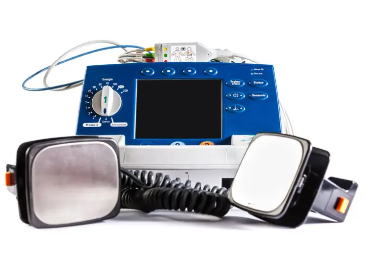 Défibrillateur bleu avec électrodes. La question "peut-on mourir avec un défibrillateur implanté" reste ouverte, mais cet appareil externe est conçu pour sauver des vies.