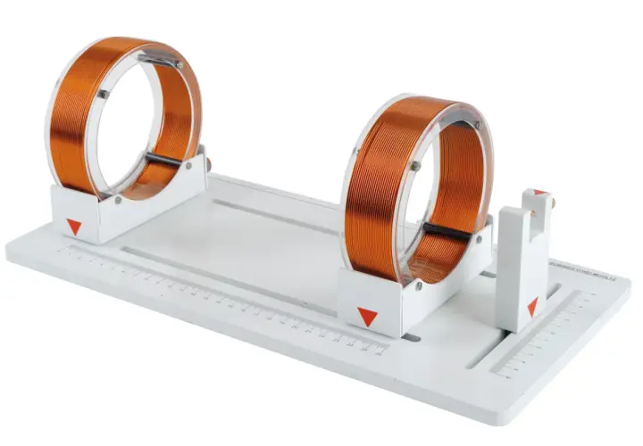Deux bobines de Helmholtz en cuivre sur un support blanc avec une règle graduée.