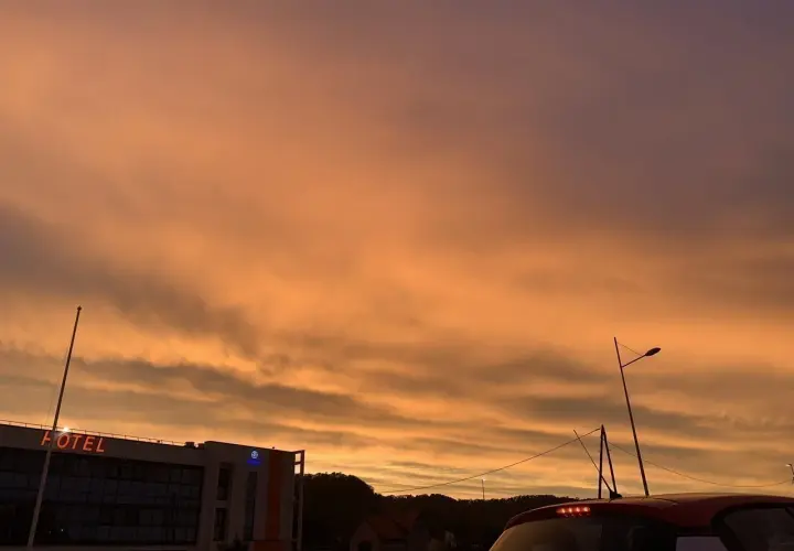 Le ciel est orange, un spectacle magnifique au-dessus d'un hôtel et d'une voiture.