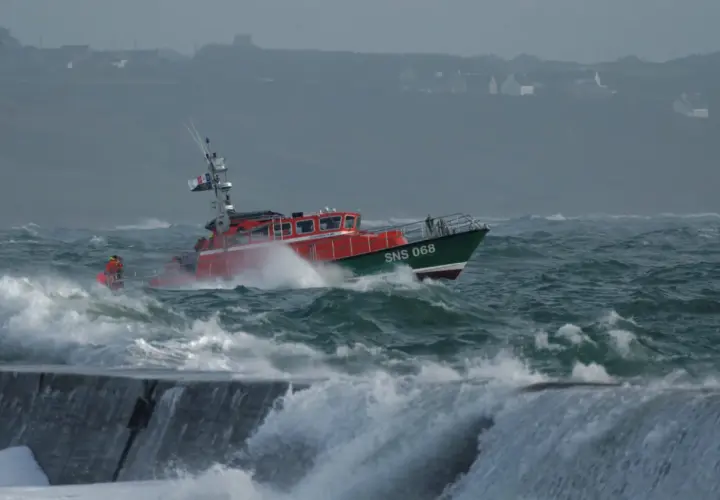 Bateau de sauvetage SNS 068 naviguant dans une mer agitée, sous un fort coup de vent. Les vagues déferlent sur la proue.