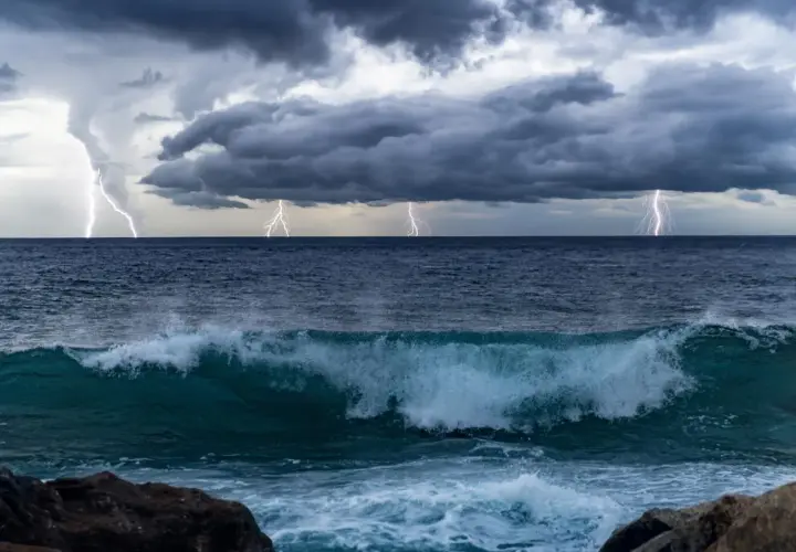 Orage spectaculaire sur l'océan Pacifique, éclairs zébrant un ciel menaçant au-dessus de vagues déferlantes.