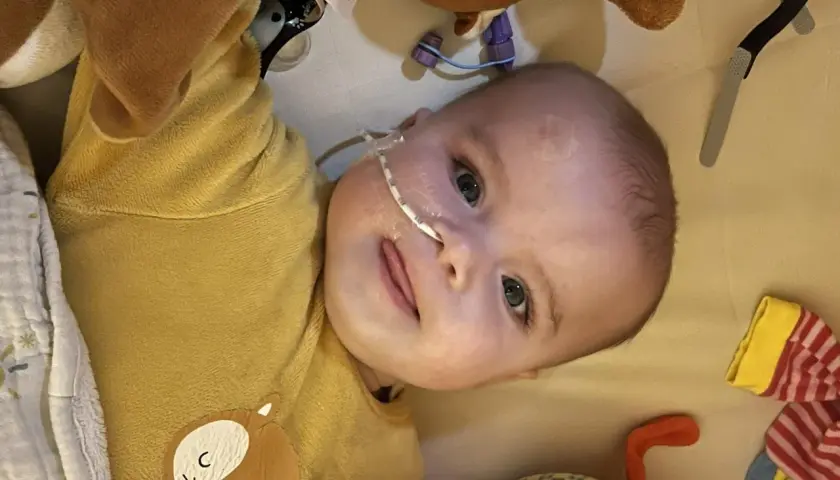 Un bébé avec une sonde nasogastrique, entouré de peluches. L'espoir d'une vie longue malgré la maladie de Pompe.