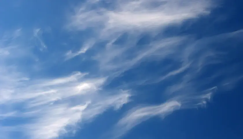 Ciel bleu profond parsemé de nuages fins et filandreux, comme des pinceaux de lumière dans le ciel.