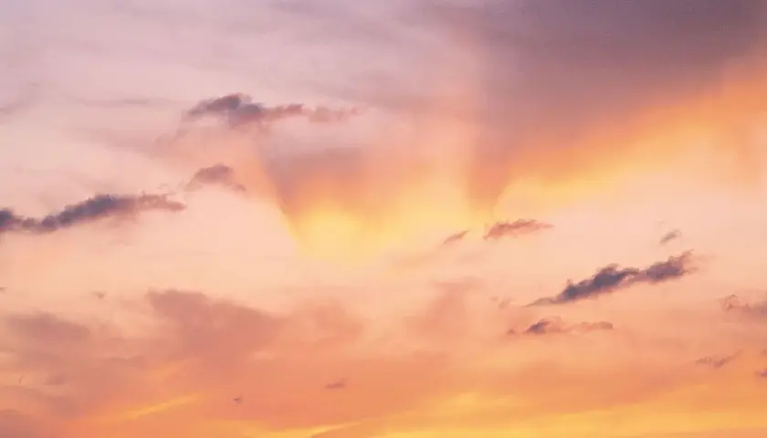 Le ciel est rose, teinté d'orange et de jaune, avec des nuages sombres. Une douce lumière filtre, expliquant pourquoi le ciel est rose.
