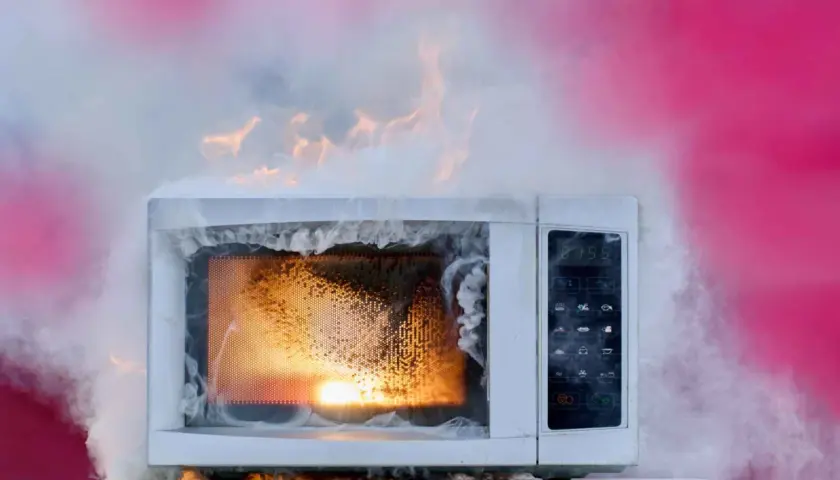 Un micro-ondes en feu, dégageant une épaisse fumée blanche et des flammes orangées. Un véritable danger micro onde.