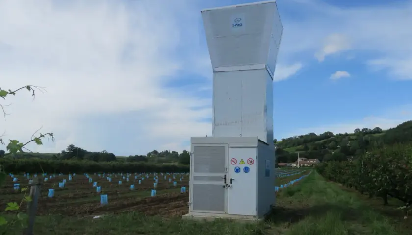 Un canon anti-grêle SPAG se dresse dans un vignoble, prêt à protéger les jeunes plants des orages.