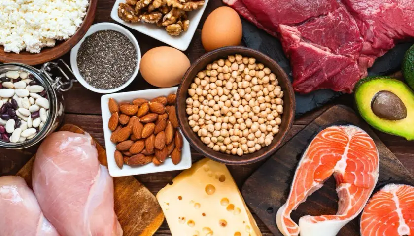 Assortiment d'aliments riches en fer : viande rouge, saumon, poulet, œufs, fromage, amandes, noix, pois chiches, haricots, graines de chia et cottage cheese.