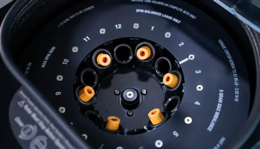 Rotor de centrifugeuse avec des tubes à essai orange. Indique "MAX RPM 5200" pour la centrifugation.