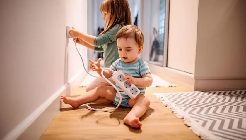 Deux enfants jouent avec des prises électriques, un danger potentiel d'électricité dans le corps.