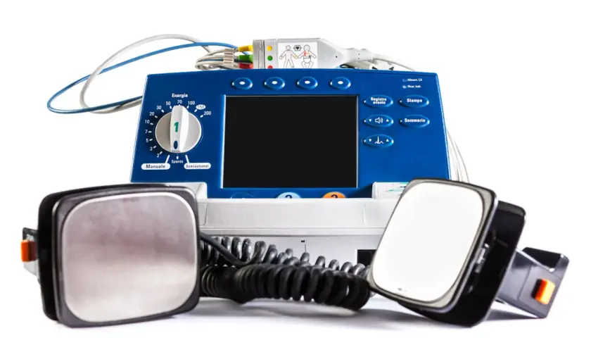Défibrillateur bleu avec électrodes. La question "peut-on mourir avec un défibrillateur implanté" reste ouverte, mais cet appareil externe est conçu pour sauver des vies.