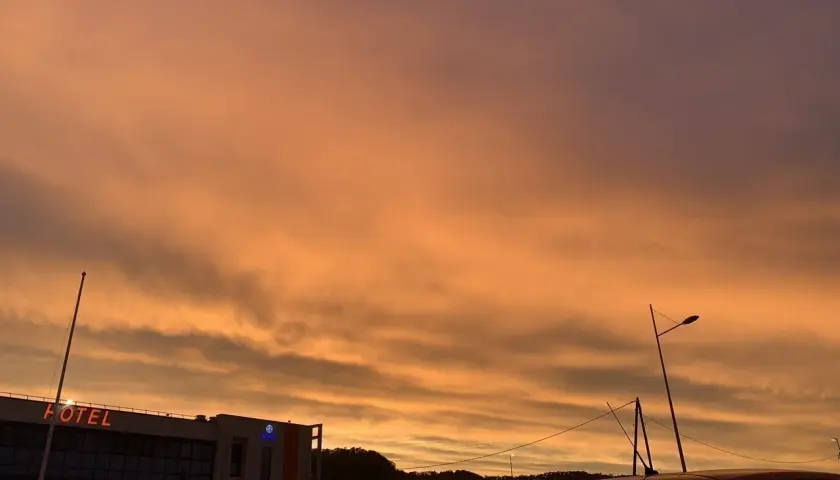 Le ciel est orange, un spectacle magnifique au-dessus d'un hôtel et d'une voiture.