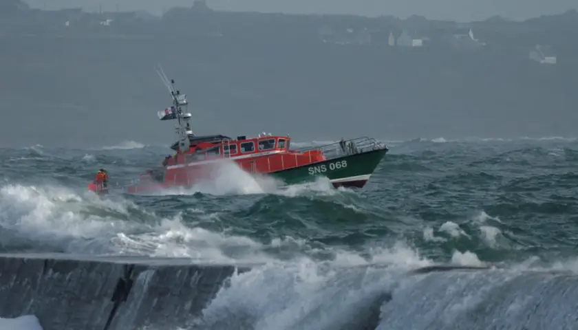 Bateau de sauvetage SNS 068 naviguant dans une mer agitée, sous un fort coup de vent. Les vagues déferlent sur la proue.