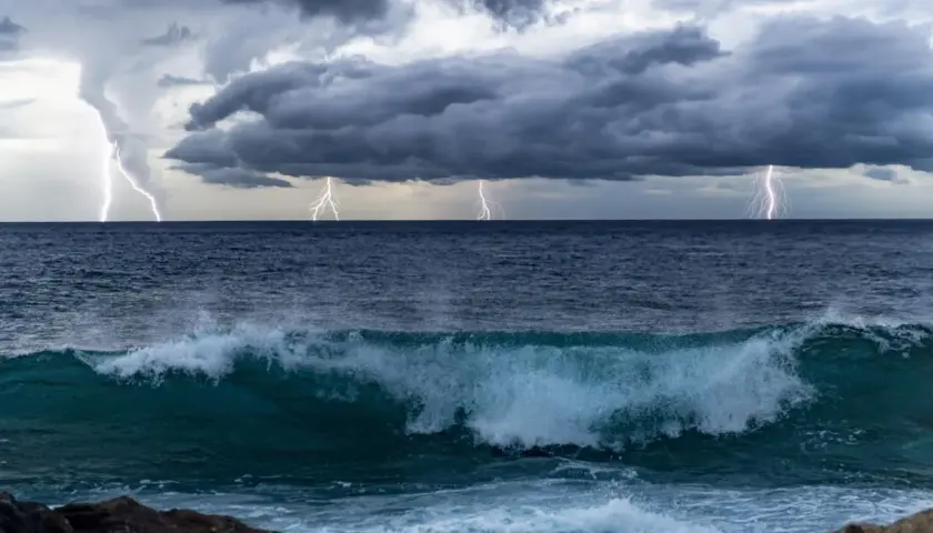 Orage spectaculaire sur l'océan Pacifique, éclairs zébrant un ciel menaçant au-dessus de vagues déferlantes.