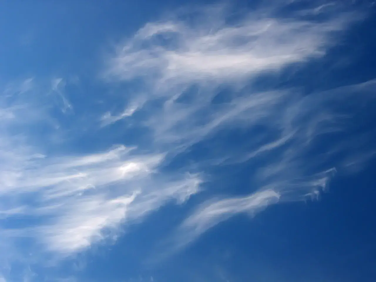 Ciel bleu profond parsemé de nuages fins et filandreux, comme des pinceaux de lumière dans le ciel.