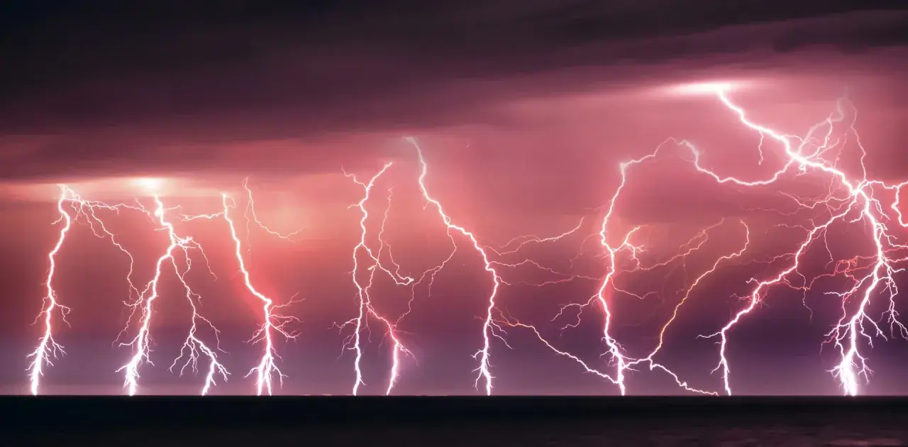 Un ciel orageux aux teintes roses et violettes, illuminé par un **éclair de chaleur** spectaculaire qui déchire l'horizon au-dessus de la mer.