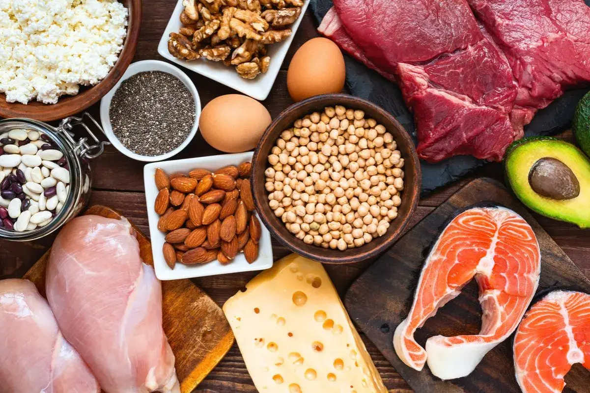 Assortiment d'aliments riches en fer : viande rouge, saumon, poulet, œufs, fromage, amandes, noix, pois chiches, haricots, graines de chia et cottage cheese.