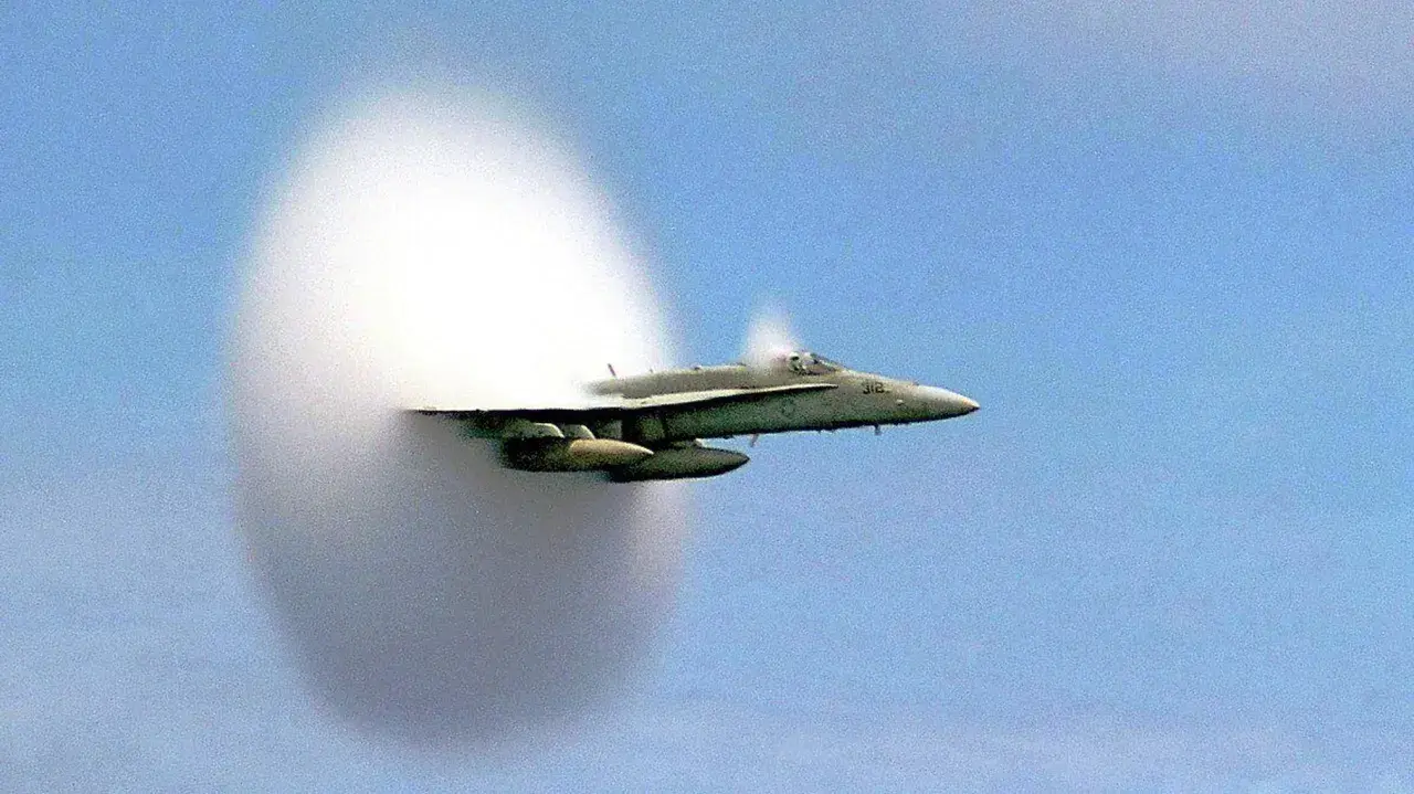 Un avion de chasse franchit le mur du son, créant un nuage de condensation spectaculaire autour de lui.