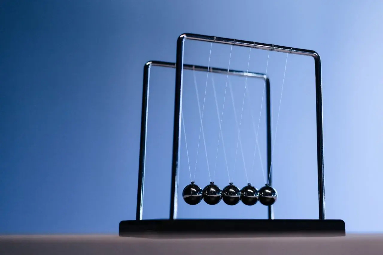Un pendule de Newton, avec ses billes d'acier suspendues, illustre la conservation de l'énergie et de la quantité de mouvement. À quoi ça sert ? À observer la physique en action !
