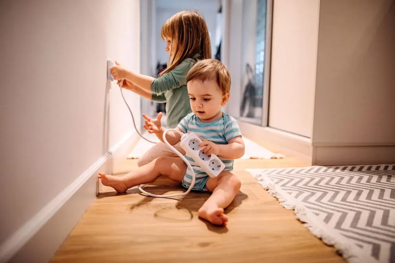 Deux enfants jouent avec des prises électriques, un danger potentiel d'électricité dans le corps.