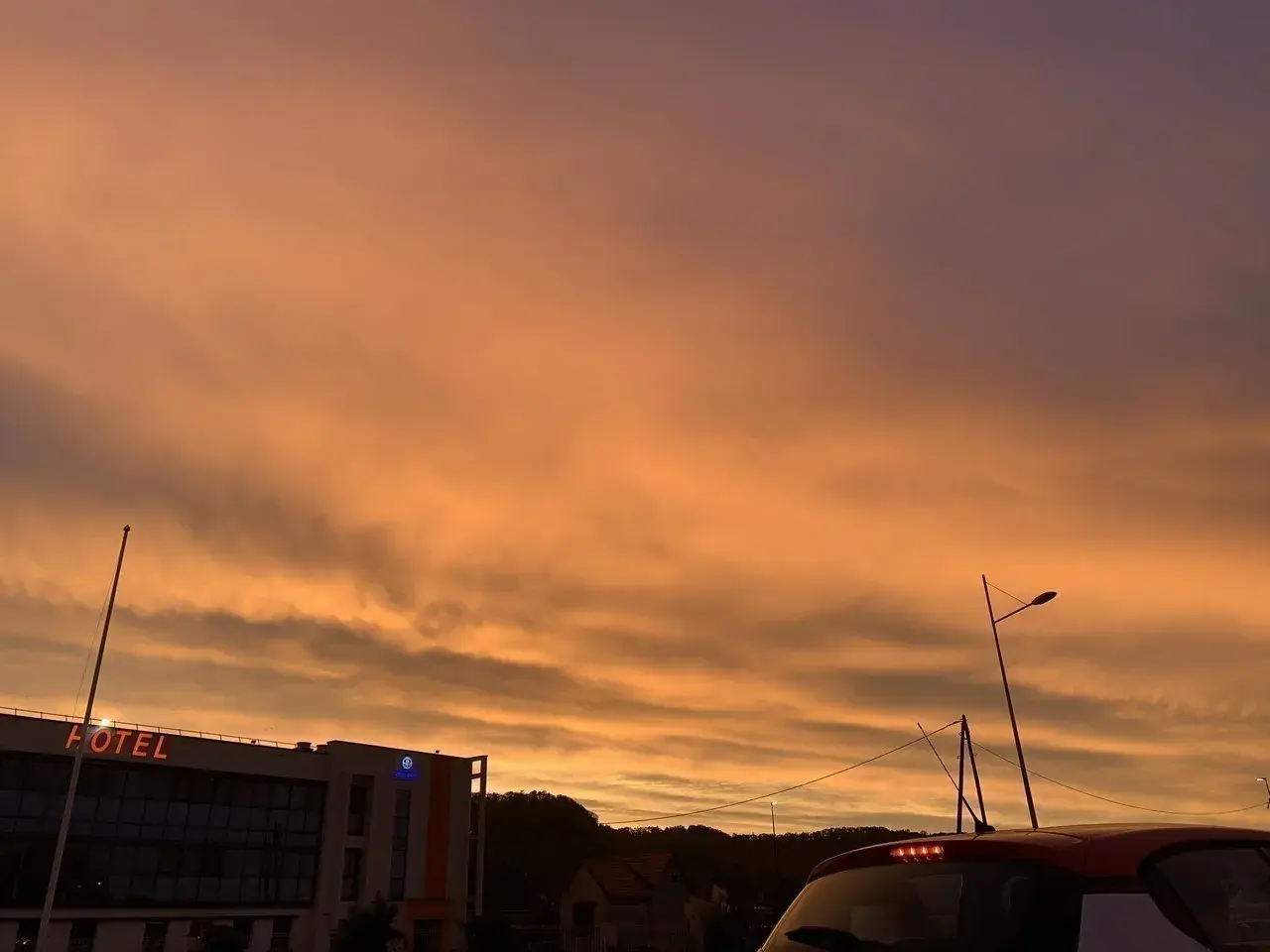 Le ciel est orange, un spectacle magnifique au-dessus d'un hôtel et d'une voiture.