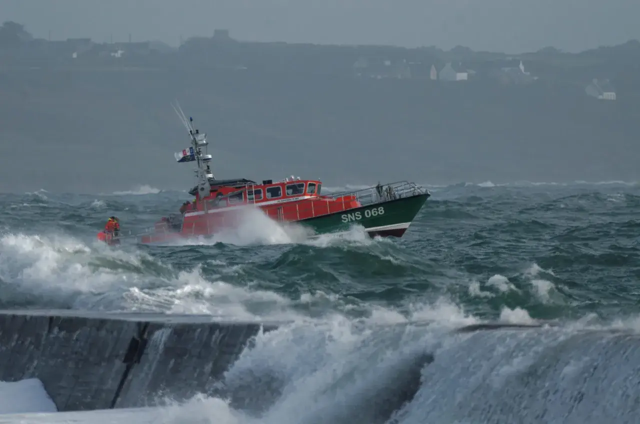 Bateau de sauvetage SNS 068 naviguant dans une mer agitée, sous un fort coup de vent. Les vagues déferlent sur la proue.