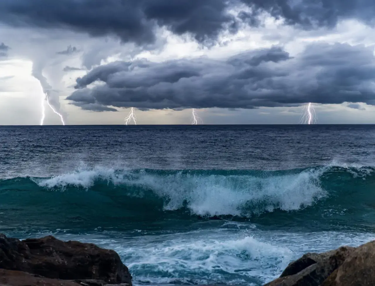 Orage spectaculaire sur l'océan Pacifique, éclairs zébrant un ciel menaçant au-dessus de vagues déferlantes.