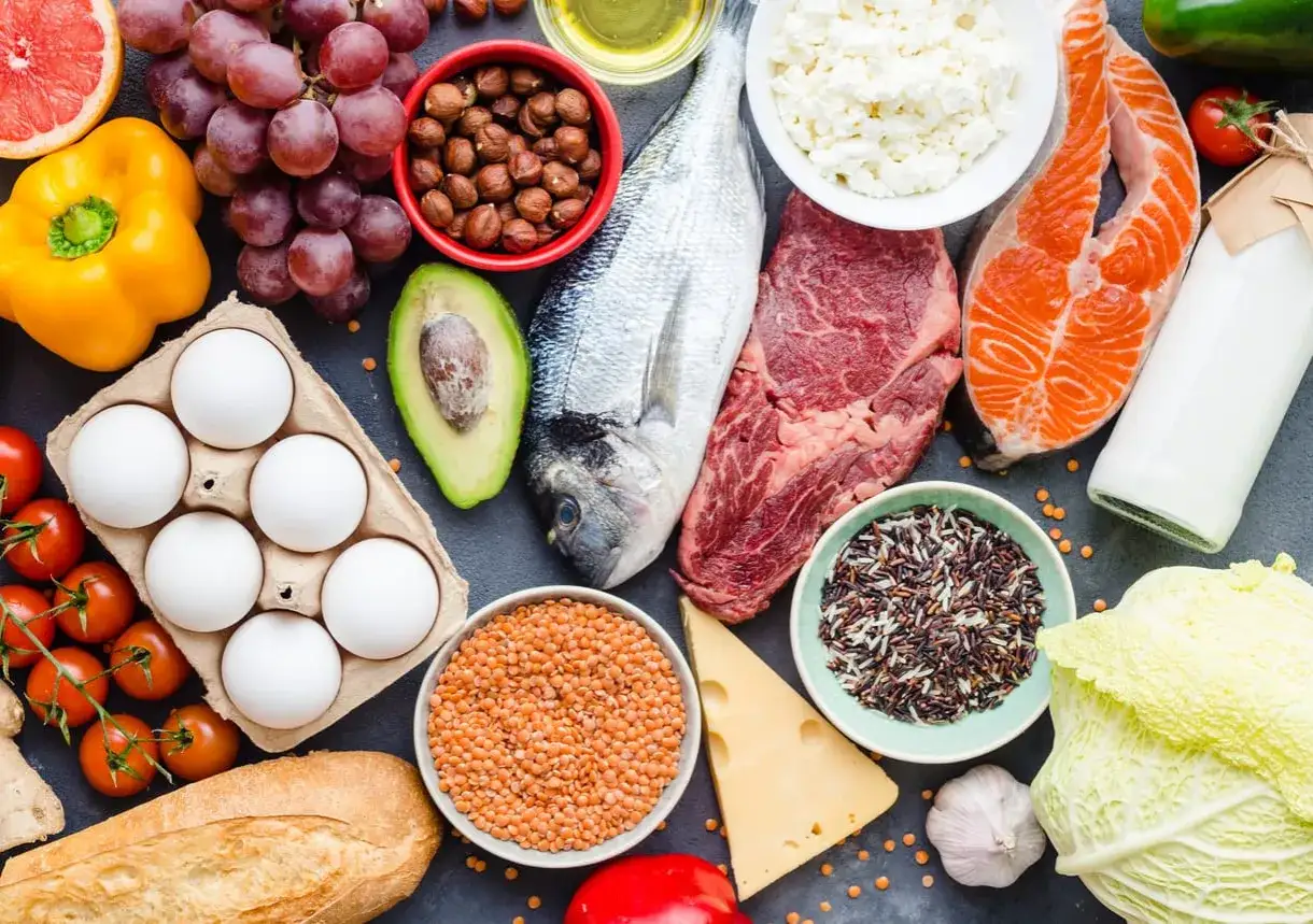Assortiment d'aliments riches en protéines : poisson, viande, œufs, produits laitiers, légumineuses, noix, céréales. Ces aliments fournissent les 9 acides aminés essentiels.