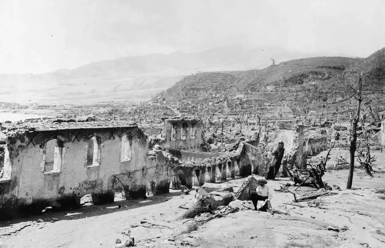 Un survivant regarde les ruines d'une ville dévastée par une éruption volcanique sur une montagne pelée. L'éruption de 1902 a tout détruit.